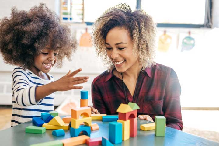 teacher and child playing with colorful blocks and smiling