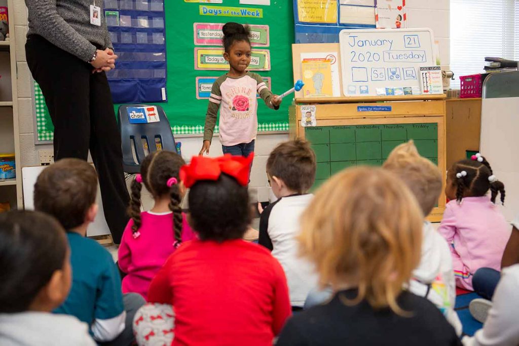 Young girl choosing a classmate with a pointer during whole group.