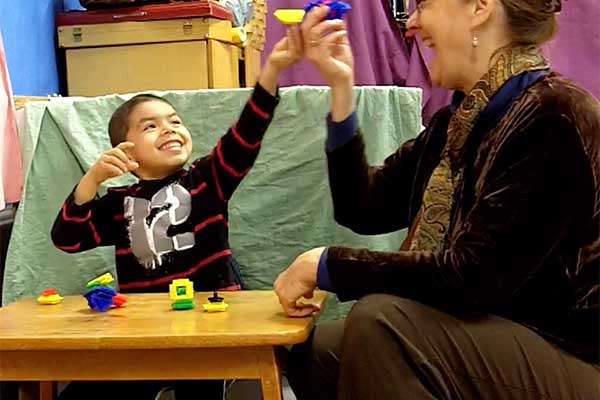 A boy and his teacher playing with toys together