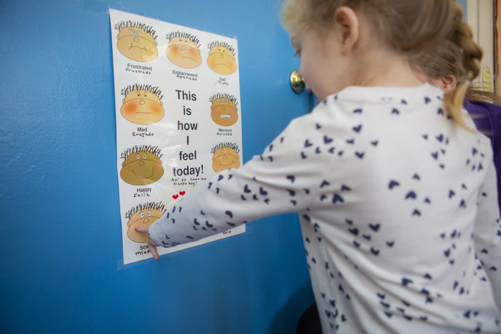 Young girl pointing to emotion chart