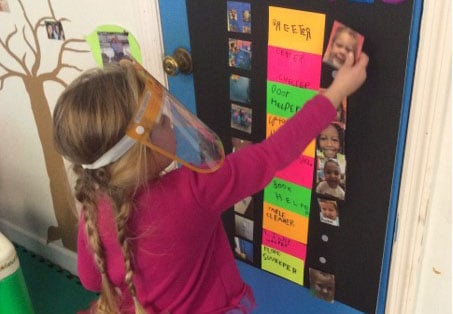 Girl wearing a face shield and using a helper chart