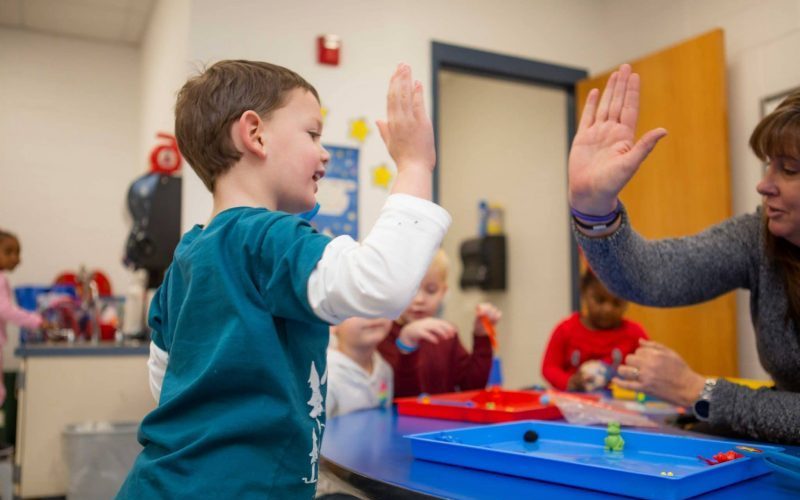 Child and teacher high five and smile