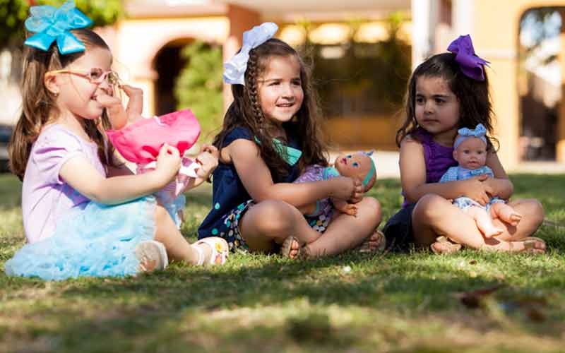 three girls playing with dolls