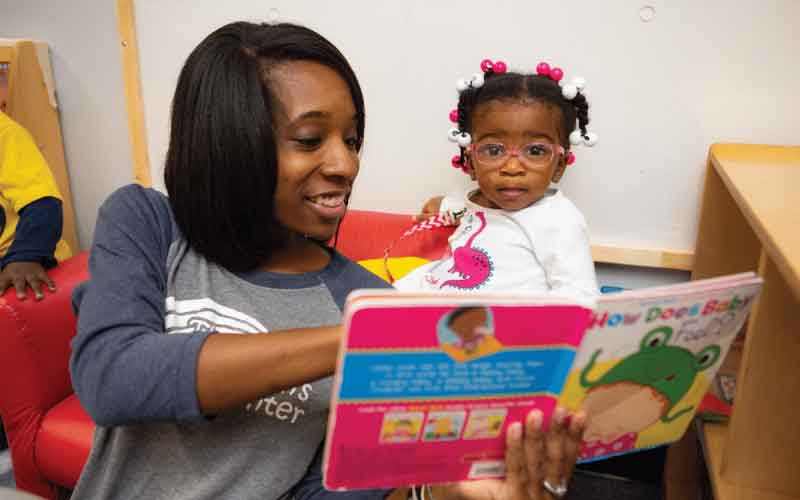 Teacher and baby look at book about feelings together